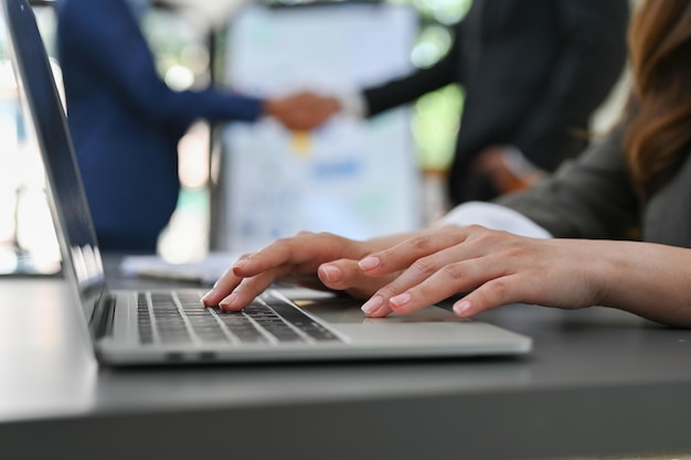 Gros plan sur l'image vue de côté Une femme d'affaires à l'aide d'un ordinateur portable en tapant sur le clavier