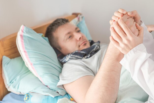 Gros plan : Infirmière médecin en uniforme tenant le patient de l'homme à la main. Le médecin soutient les soins de santé et encourage le patient dans la vie.