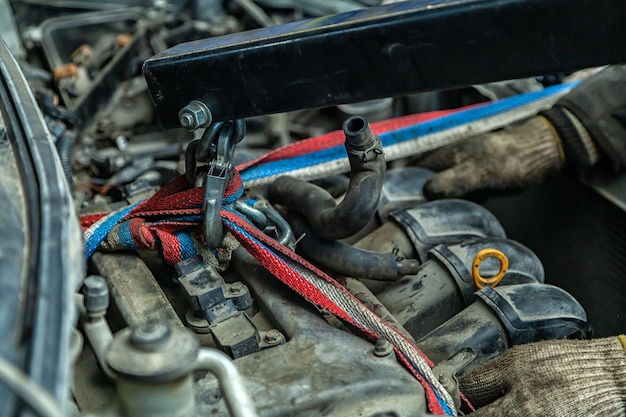 Gros plan de l'installation du moteur sur une vieille voiture à l'aide d'une grue manuelle pneumatique dans l'atelier de réparation automobile Le travail des mécaniciens automobiles pour retirer le moteur