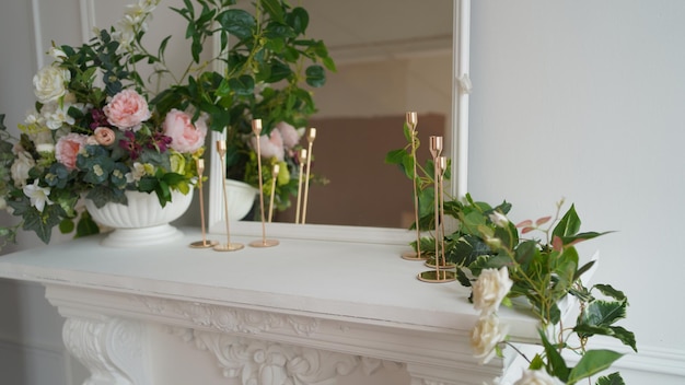 Gros plan de l'intérieur de l'un des coins de la pièce Grand miroir avec fleurs décoratives et bougies sur tableau blanc