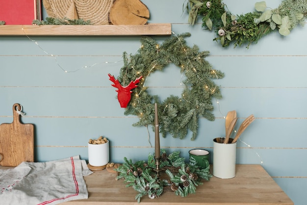 Gros plan de l'intérieur de la cuisine Décoration de Noël Couronne de fleurs de Noël accrochée au mur Mur en bois de menthe Comptoirs en bois avec ustensiles de cuisine Design scandinave vintage