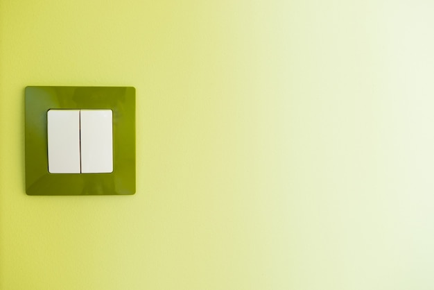Gros plan sur l'interrupteur de lumière blanche sur un mur vert avec fond