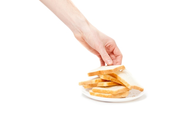 Gros plan isolé sur une main masculine prenant un morceau de pain dans une assiette