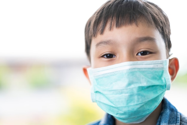 Photo gros plan isolé visage d'enfant asiatique garçon enfants portant un masque vert couvrant la bouche nez nez, concept de protection contre la maladie du virus corona, les germes et la transmission de l'air