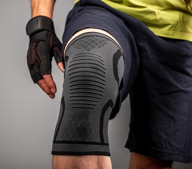 Gros plan de la jambe du bodybuilder de l'athlète portant une attelle de soutien du genou manchon élastique de bandage de la rotule pour la compression