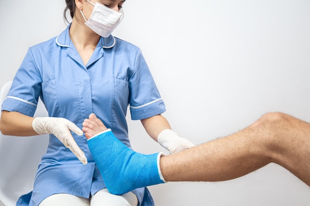 Gros plan de la jambe d'un homme dans un plâtre et une attelle bleue après un bandage dans un hôpital.