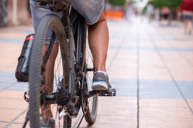 Gros plan sur les jambes d'une femme décontractée tout en exécutant son vélo électrique dans une rue urbaine