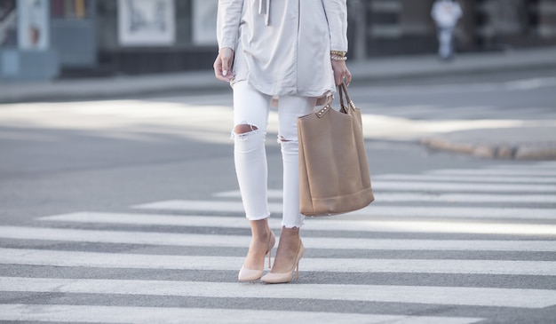 gros plan des jambes de femme marchant sur le passage pour piétons. La femme porte des chaussures à talons hauts.