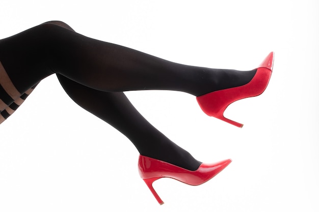 Gros plan des jambes des femmes en collants à motifs et talons hauts rouges