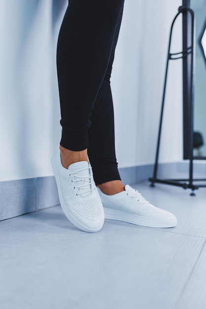 Gros plan des jambes des femmes dans des baskets en cuir blanc en cuir naturelCollection de chaussures d'été pour femmes