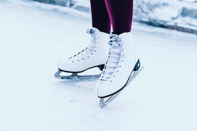 Gros plan des jambes de femmes sur des patins en hiver sur une patinoire ouverte.