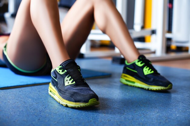 Photo gros plan des jambes d'une jeune fille exerçant des abdominaux dans la salle de sport