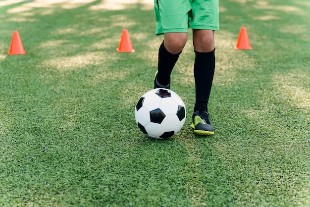 Gros plan des jambes et des pieds du footballeur sur l'herbe verte