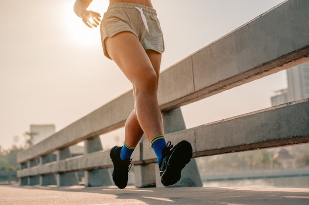 Gros plan des jambesFemmes asiatiques faisant du jogging dans l'entraînement du matin à la ville Une ville qui vit en bonne santé