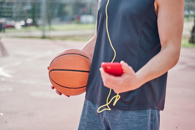 Gros plan d'un jeune athlète sur un terrain de basket s'entraînant tout en écoutant de la musique