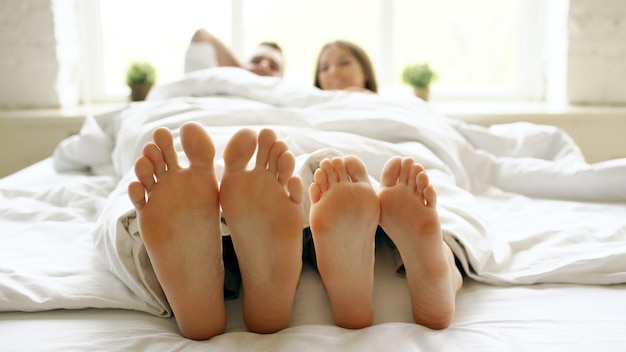 Gros plan d'un jeune couple beau et aimant jouer et danser leurs pieds sous une couverture