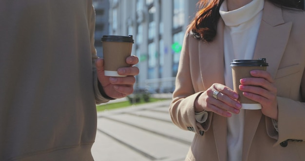 Gros plan sur un jeune couple caucasien buvant du café et parlant debout ensemble dans la rue