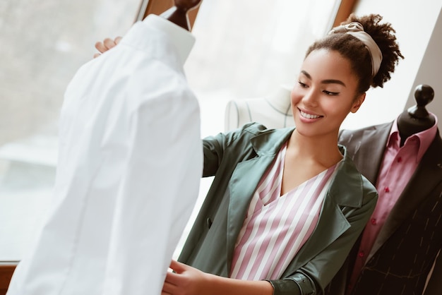 Gros plan d'un jeune designer avec du ruban adhésif mesure une chemise blanche femme souriante