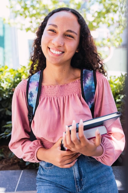 Gros plan sur une jeune étudiante latine heureuse tenant ses livres à l'extérieur du campus. Notion d'éducation