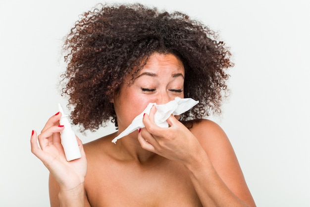 Gros plan d'une jeune femme afro-américaine à l'aide d'un spray nasal