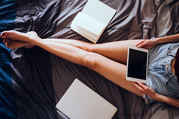 Gros plan de jeune femme à l&#39;aide de tablette tout en étant assis sur son lit, filtre à grains Films.