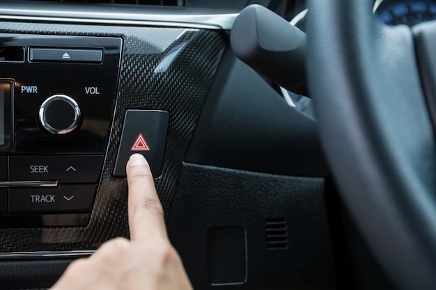 Gros plan de jeune femme en appuyant sur le bouton d&#39;urgence sur le tableau de bord voiture sport.