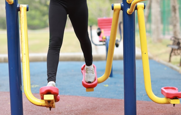 Gros plan sur une jeune femme asiatique en bonne santé en vêtements de sport relaxants sur une machine d'exercice publique en plein air.