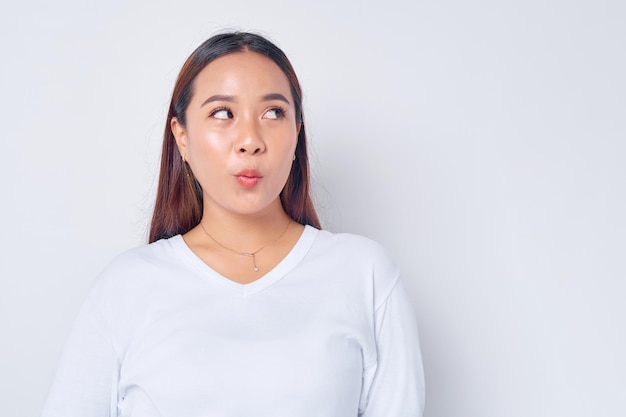 Gros plan jeune femme blonde asiatique portant un t-shirt blanc décontracté regardant de côté avec une expression étonnée isolée sur fond blanc concept de mode de vie des gens