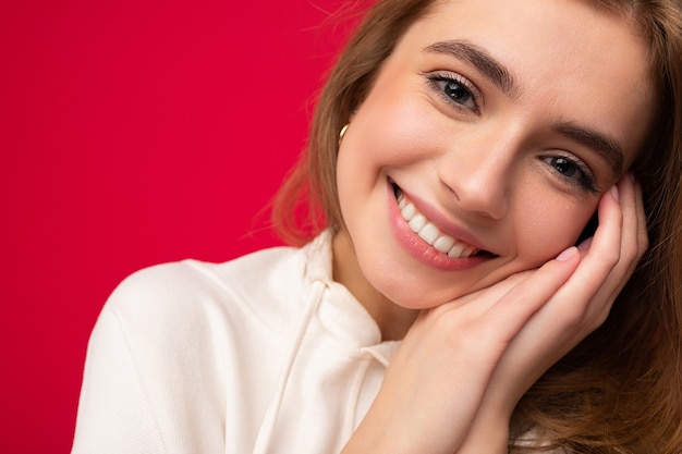 Gros plan de jeune femme blonde souriante belle avec des émotions sincères isolé sur fond