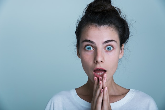 Gros plan d'une jeune femme choquée portant un t-shirt isolé sur fond bleu