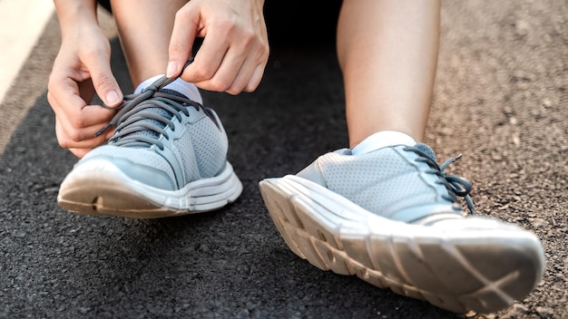 Gros plan d'une jeune femme coureuse attachant ses lacets concept de santé et de remise en forme