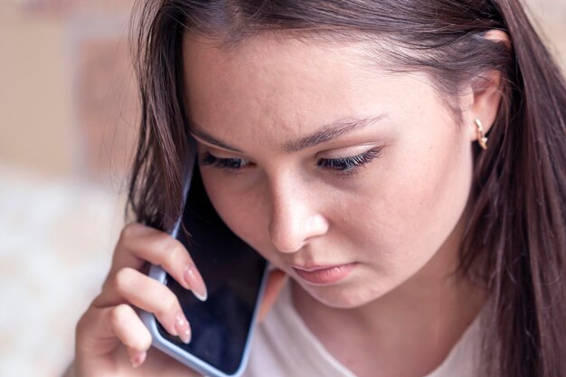 Gros plan d'une jeune femme écoutant un message sur son téléphone