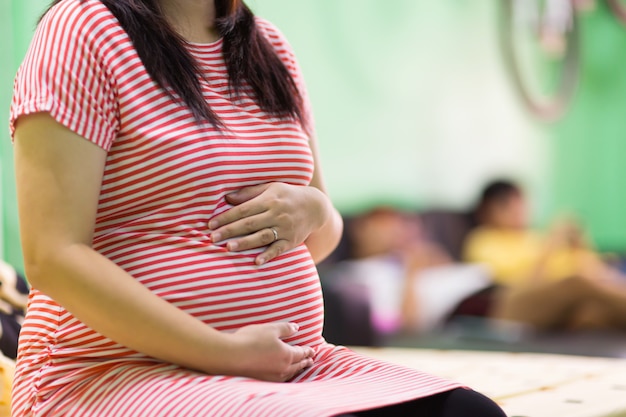 Gros plan d&#39;une jeune femme enceinte assise sur un canapé à la maison