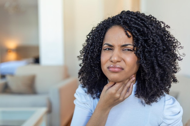 Gros plan d'une jeune femme frottant ses amygdales enflammées problème d'amygdalite recadrée Femme avec problème de glande thyroïde touchant son cou fille a mal à la gorge