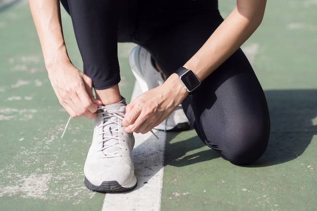 Gros plan d&#39;une jeune femme lace sa chaussure prête à l&#39;entraînement sur l&#39;exercice dans le parc