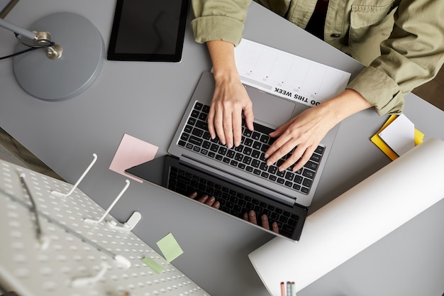 Gros plan d'une jeune femme moderne utilisant un ordinateur portable alors qu'il était assis au bureau,