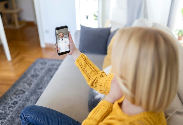 Gros plan d'une jeune femme parlant à son médecin lors d'un appel vidéo