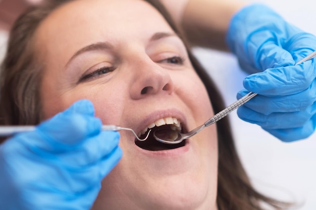 Gros plan jeune femme recevant des soins dentaires d'un dentiste qualifié à l'aide d'outils dentaires