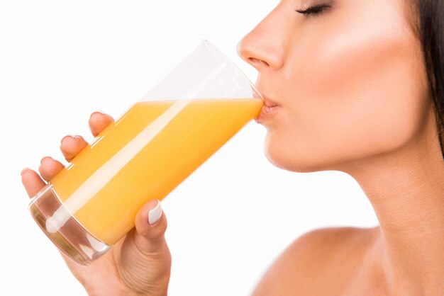 Gros plan d'une jeune femme sexy buvant du jus d'orange