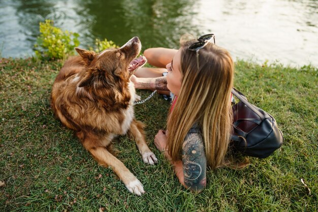 Gros plan d'une jeune femme avec son chien assis sur l'herbe dans le parc