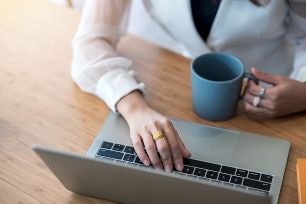 Gros plan de jeune femme travaillant sur ordinateur portable à table au bureau