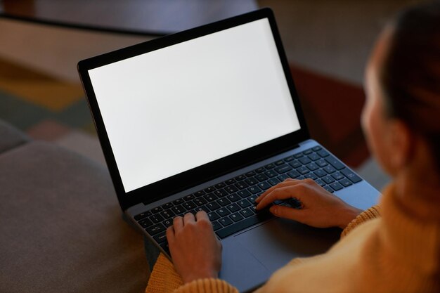 Gros plan jeune femme utilisant un ordinateur portable avec écran blanc dans un cadre sombre