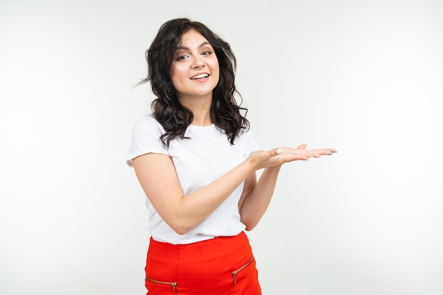 Gros plan d'une jeune fille brune dans un T-shirt blanc avec main dans la main sur un fond de studio blanc.