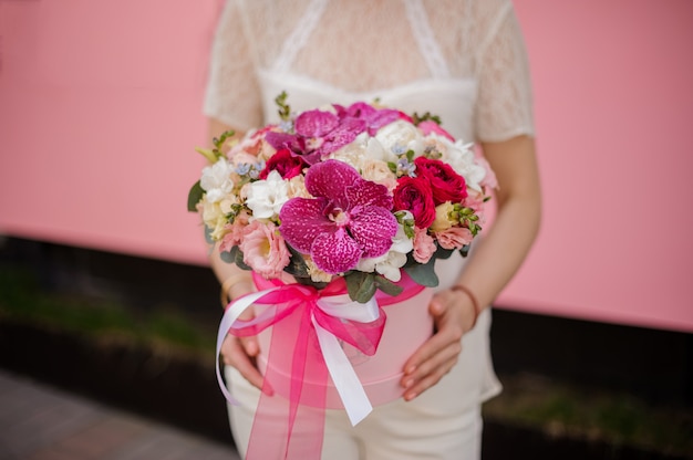 Gros plan d'une jeune fille tenant un bouquet dans une boîte à chapeau avec un arc