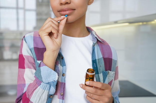 Gros plan jeune fille tenant des pilules prenant des vitamines complément alimentaire pour la santé des cheveux de la peau de la femme