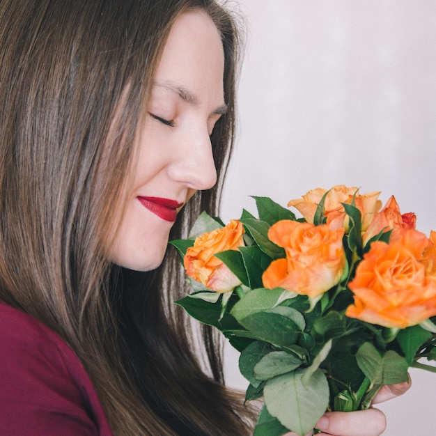 Photo gros plan, jeune, fille, tenue, bouquet, roses orange, devant, elle, renifler