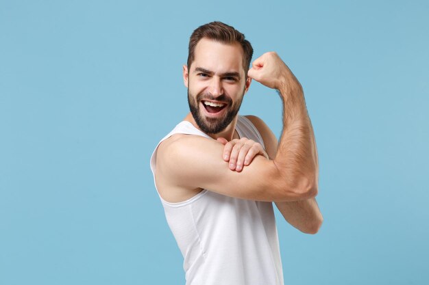 Gros plan jeune homme barbu de 20 ans peau parfaite portant une chemise blanche isolée sur fond de mur bleu pastel, portrait en studio. Concept de procédures cosmétiques de soins de la peau. Maquette d'espace de copie