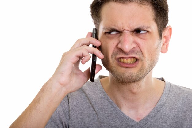 Gros plan d'un jeune homme en colère parlant au téléphone mobile
