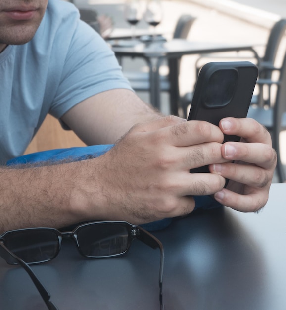 Gros plan d'un jeune homme interagissant avec son smartphone. Notion de technologie.