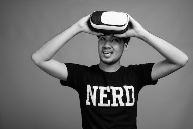 Gros plan d'un jeune homme nerd asiatique à l'aide d'un casque de réalité virtuelle